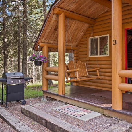Image of cabin porch with porch swing, flowers, and grill at Nugget RV Park